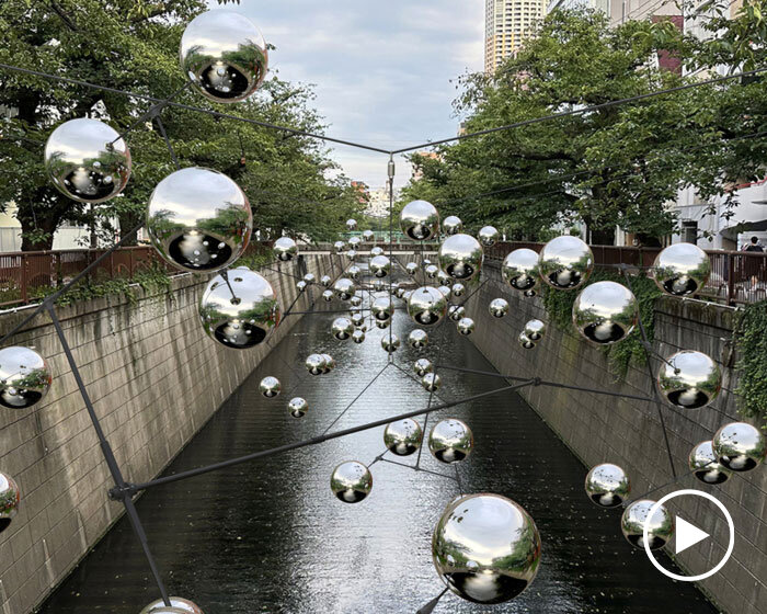 reflective spheres by vincent leroy form swirling constellation above canal in tokyo