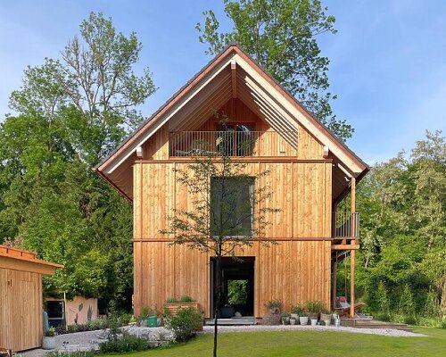 towering poplars, pines, and firs shield studiomolter’s wooden house by the river in germany