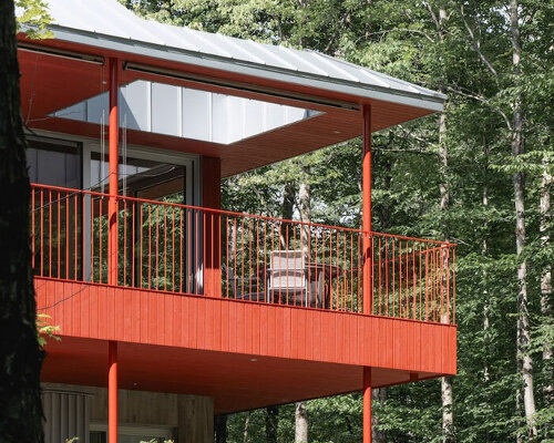 scarlet-red wood clads house by _naturehumaine floating above three streams in canada