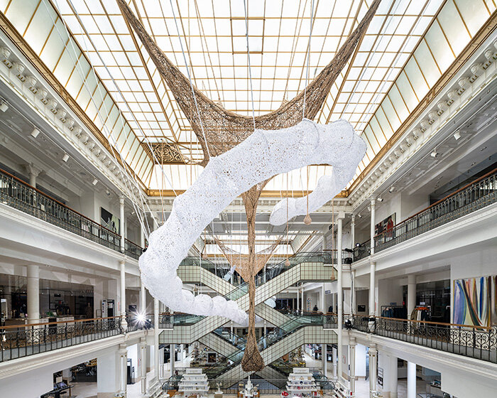 ernesto neto suspends monumental crochet serpent within le bon marché in paris