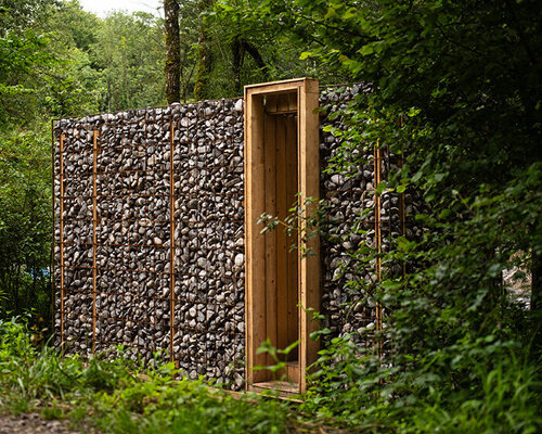 gabion walls frame tephra's stone shelter along dry riverbed in french mineral landscape