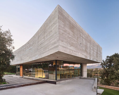 concrete-enveloped casa roble adapts to madrid's terrain with its continuous curved facade