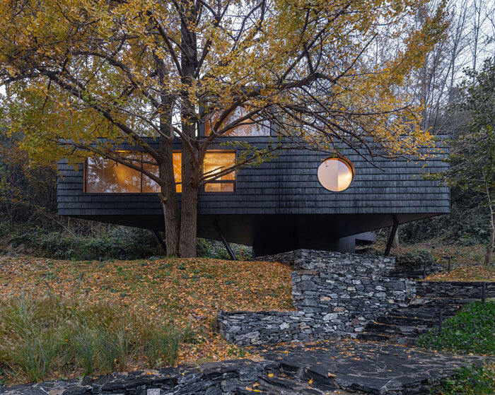 geometric openings pierce elevated treehouse clad in charred cedar planks in hubei